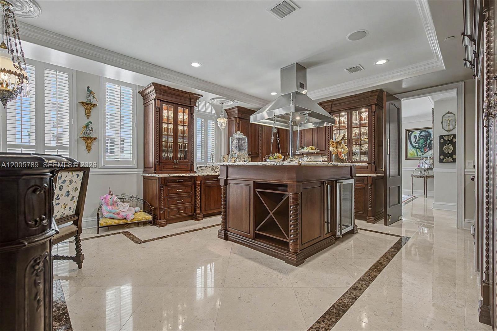A kitchen features dark wood cabinetry, a central island with wine storage, and marble flooring — 600 Coral Way # 5, Coral Gables FL 33134, CORAL GABLES, FL