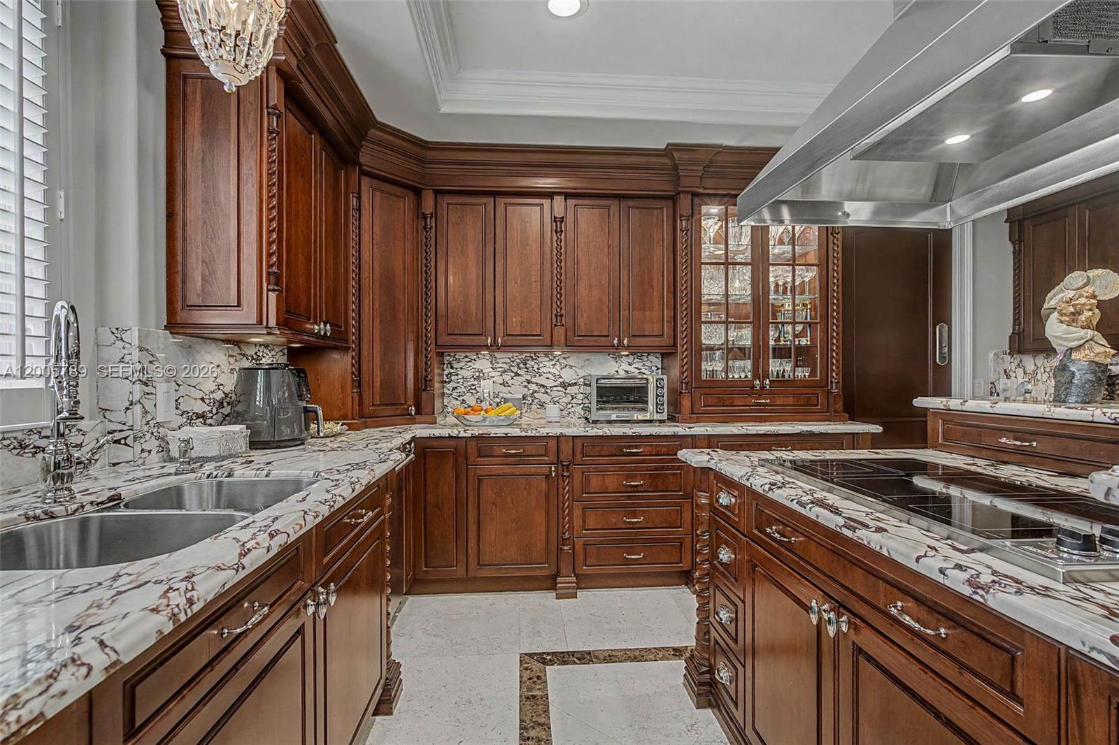 A kitchen with dark wood cabinetry, marble countertops, and a stainless steel range hood — 600 Coral Way # 5, Coral Gables FL 33134, CORAL GABLES, FL