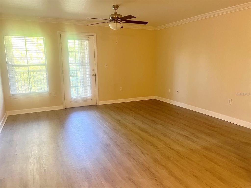 An empty room features light-colored walls, wood-look flooring, a ceiling fan, and a glass door — 18335 BRIDLE CLUB DRIVE UNIT 18335, TAMPA, FL