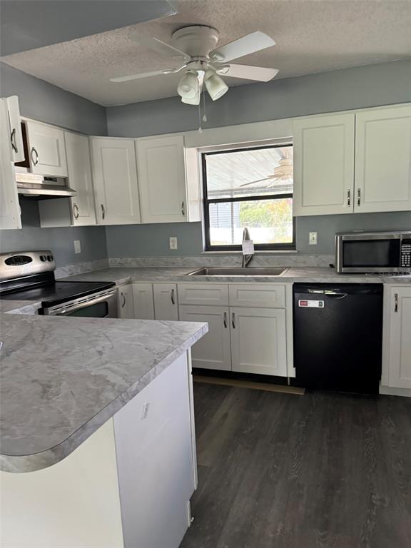 A kitchen features white cabinets, gray countertops, a stainless steel stove, and a black dishwasher — 38745 CAMBRIDGE DRIVE, ZEPHYRHILLS, FL