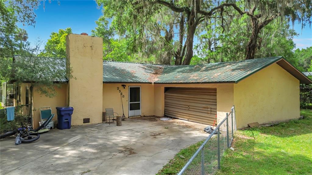 A single-story house with a metal roof, yellow stucco exterior, and an attached garage — 2548 CR 422, LAKE PANASOFFKEE, FL