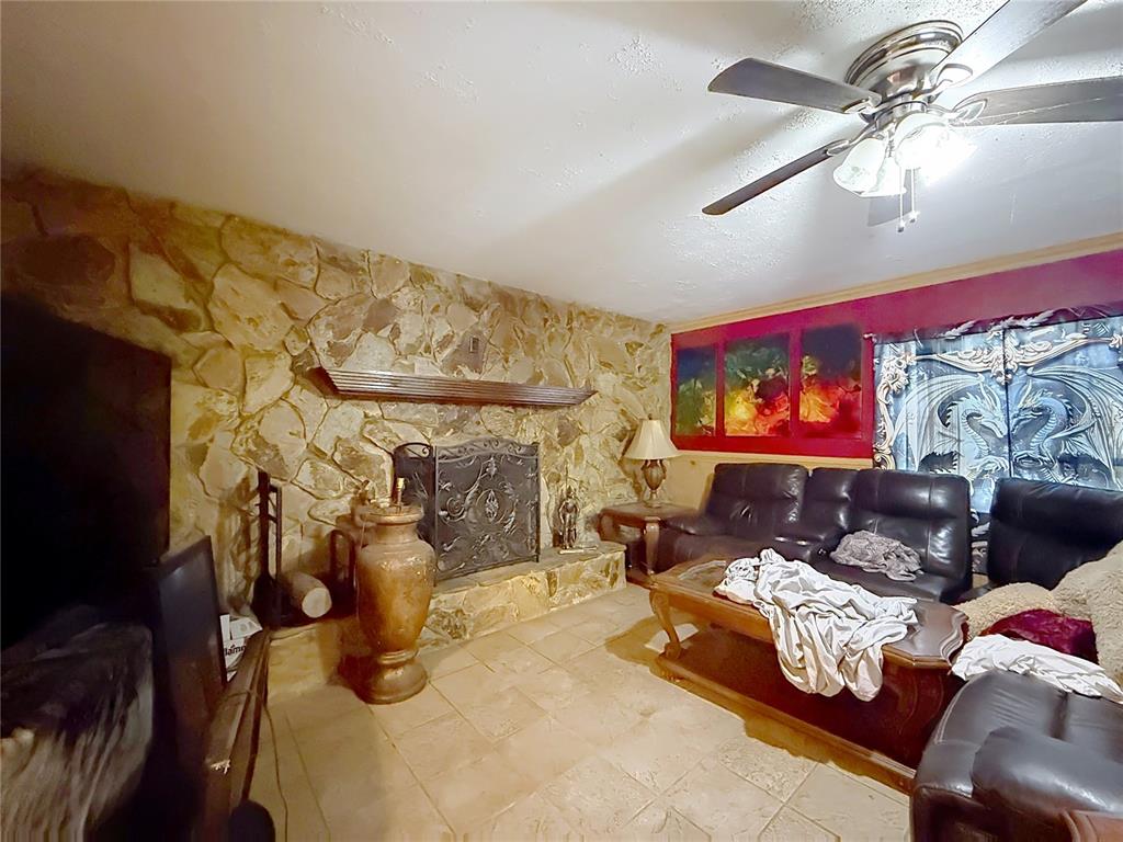 A living room features a stone fireplace, tile flooring, leather furniture, and a ceiling fan — 2548 CR 422, LAKE PANASOFFKEE, FL