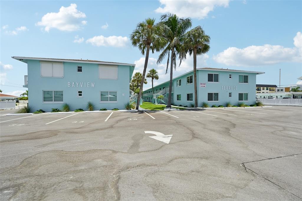 A light blue two-story apartment building with palm trees and a large parking lot — 117 7TH STREET N UNIT 1, BRADENTON BEACH, FL