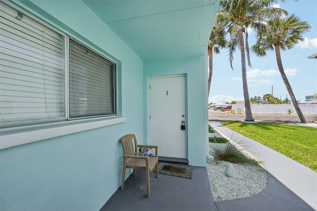 A light blue exterior wall features a white door labeled one and a wooden chair — 117 7TH STREET N UNIT 1, BRADENTON BEACH, FL