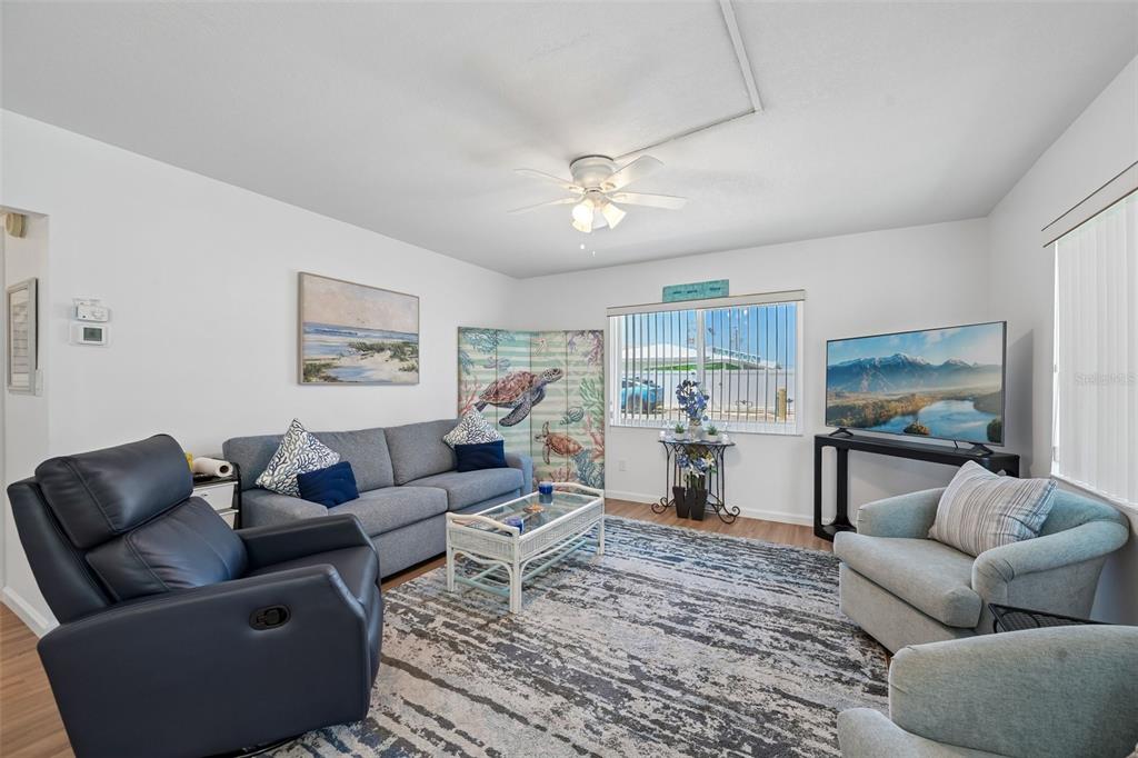 A living room features a grey sofa, a dark recliner, two armchairs, and a television — 117 7TH STREET N UNIT 1, BRADENTON BEACH, FL