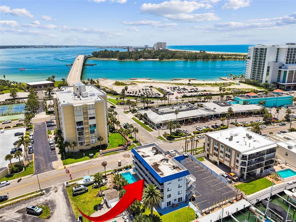 An aerial view shows a multi-story building with a blue roof and a swimming pool — 800 BAYWAY BOULEVARD UNIT 17, CLEARWATER BEACH, FL