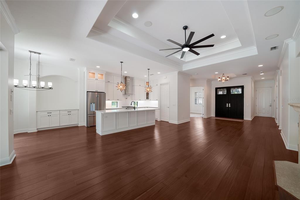 A spacious open-concept kitchen and living area features white cabinetry, a large island, and hardwood floors — 15308 HELMSDALE PLACE, LAKEWOOD RANCH, FL