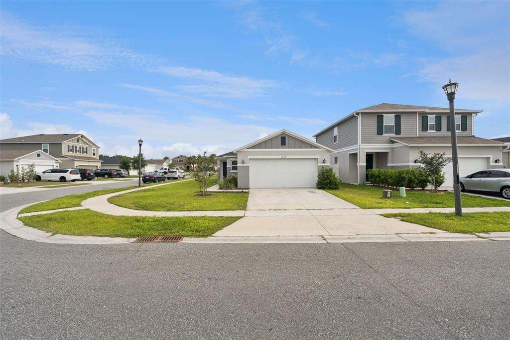 A street view of a suburban neighborhood featuring two-story and single-story houses with driveways — 1247 PAPAYA CIRCLE, DAVENPORT, FL