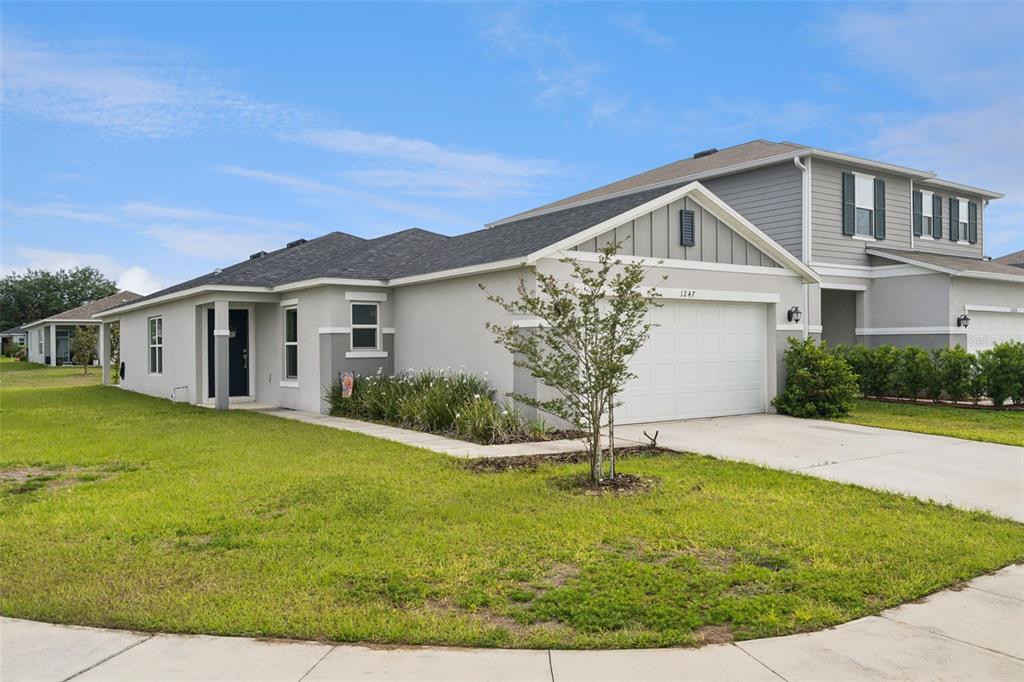 A single-story house with a white garage, gray siding, and a green lawn — 1247 PAPAYA CIRCLE, DAVENPORT, FL