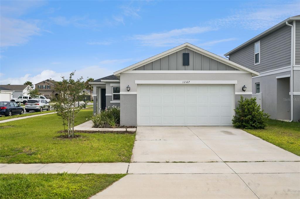 A single-story house with a gray exterior, a two-car garage, and a concrete driveway — 1247 PAPAYA CIRCLE, DAVENPORT, FL