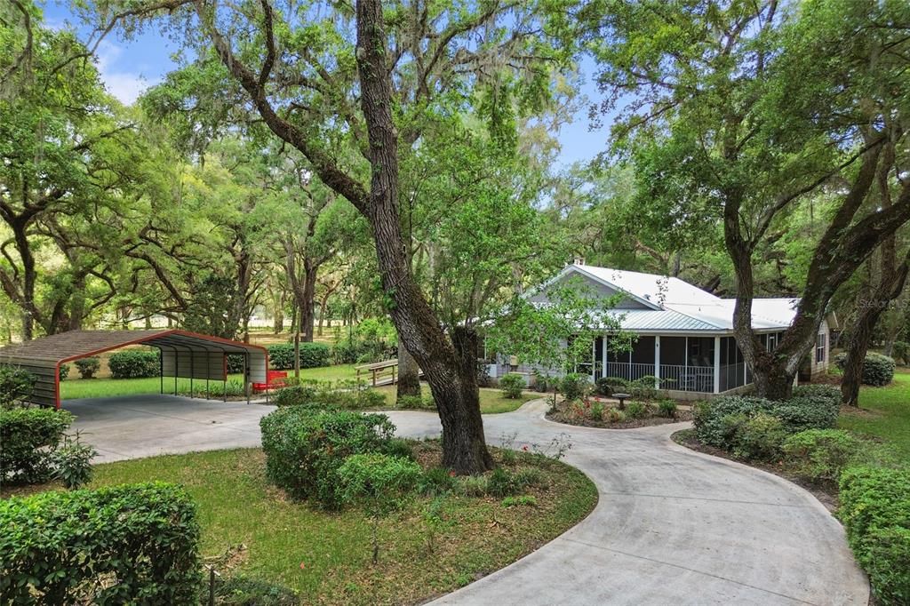 A house with a metal roof and screened porch sits behind a curved concrete driveway — 1153 CR 722, WEBSTER, FL