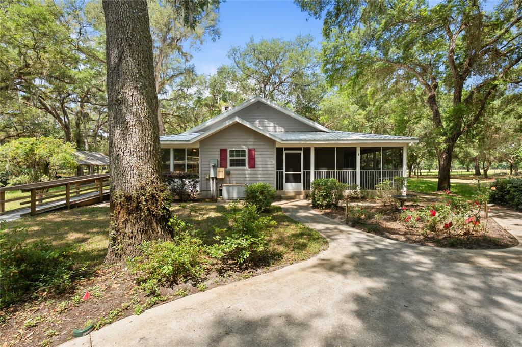 A gray house with a screened porch and a wooden ramp sits among large trees — 1153 CR 722, WEBSTER, FL