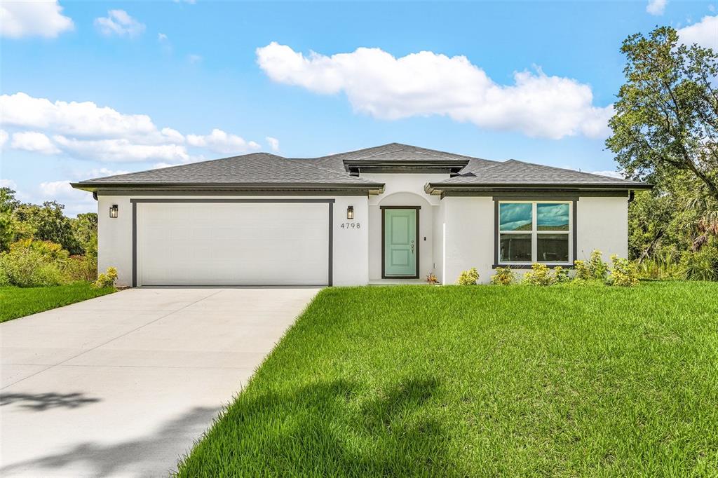 A single-story house with a white stucco exterior, a two-car garage, and a light-colored door — 4798 JODY AVENUE, NORTH PORT, FL
