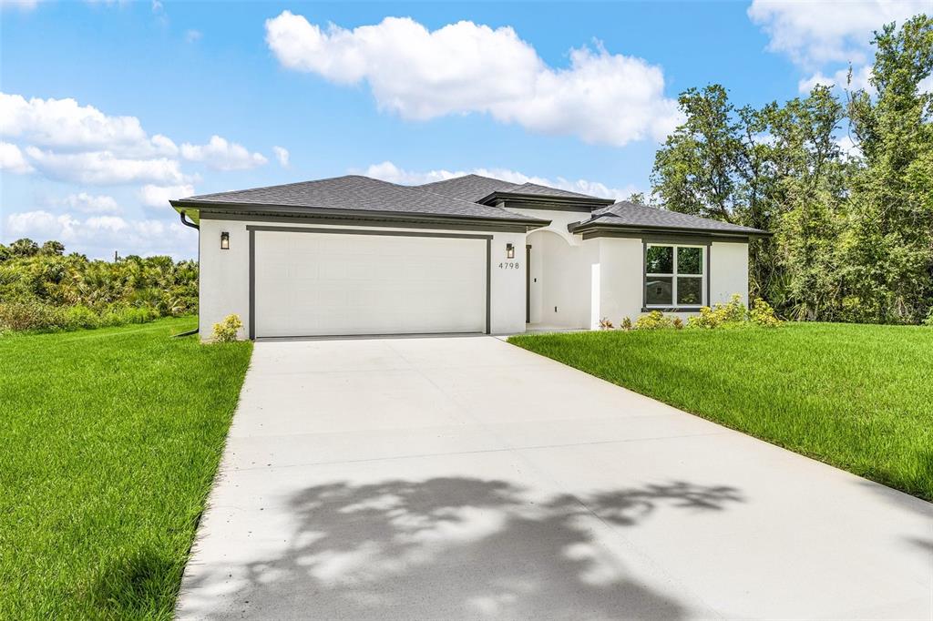 A single-story house with a white stucco exterior, dark roof, and a concrete driveway — 4798 JODY AVENUE, NORTH PORT, FL