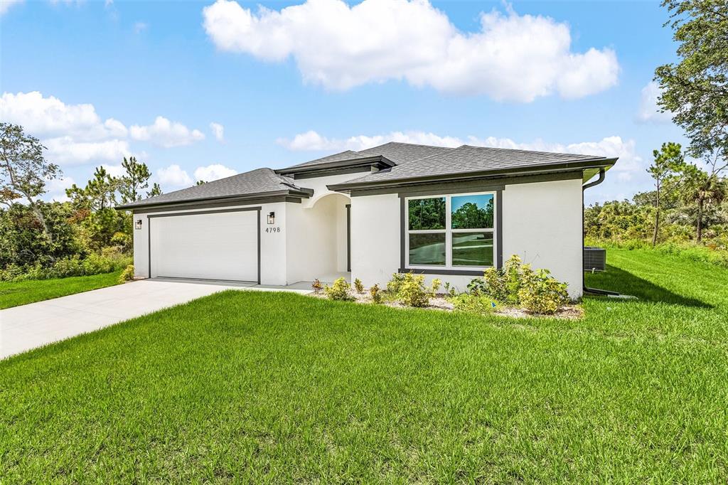 A single-story white stucco house with a two-car garage and a landscaped front yard — 4798 JODY AVENUE, NORTH PORT, FL