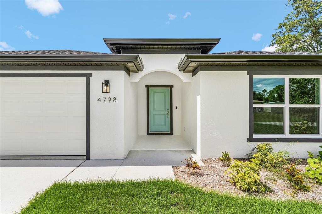 The exterior of a white house features a light blue front door and a garage — 4798 JODY AVENUE, NORTH PORT, FL