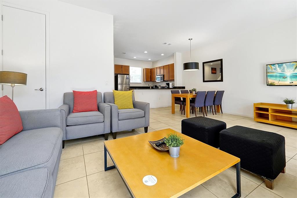 A living room with gray furniture and a wooden coffee table opens to a kitchen — 2652 CORVETTE LANE, KISSIMMEE, FL