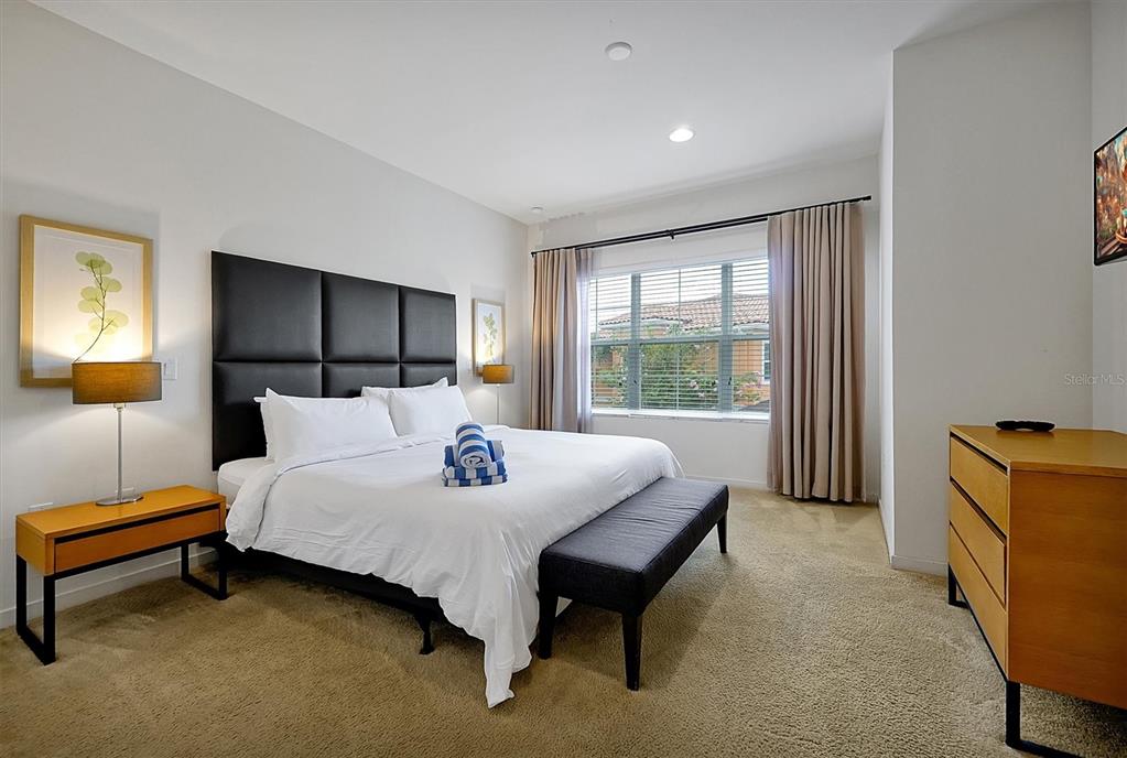 A bedroom features a king bed with a black headboard, a bench, and wooden furniture — 2652 CORVETTE LANE, KISSIMMEE, FL