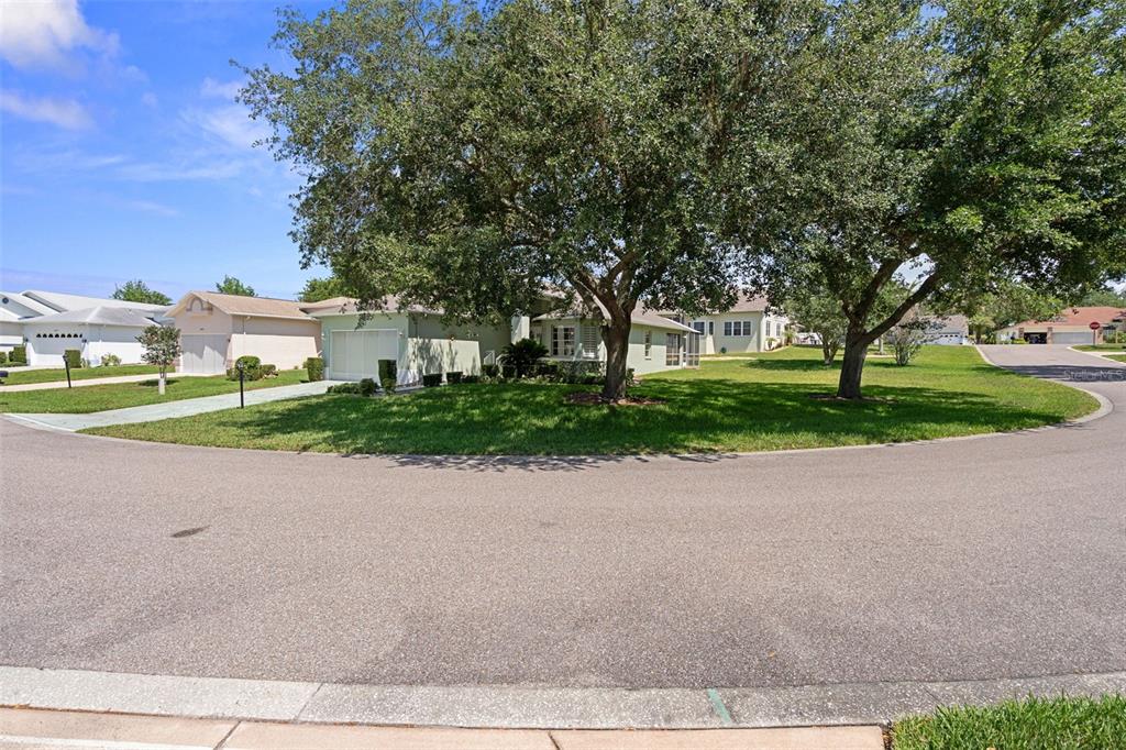 A view of a suburban house exterior with a large lawn and mature trees — 7483 BRIDGEWATER LANE, SPRING HILL, FL