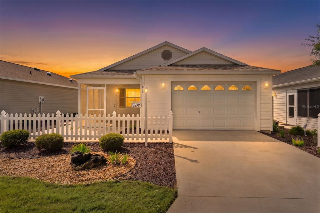 A single-story house with a white picket fence, a garage, and a screened-in front porch — 1838 ENDSLEY COURT, THE VILLAGES, FL