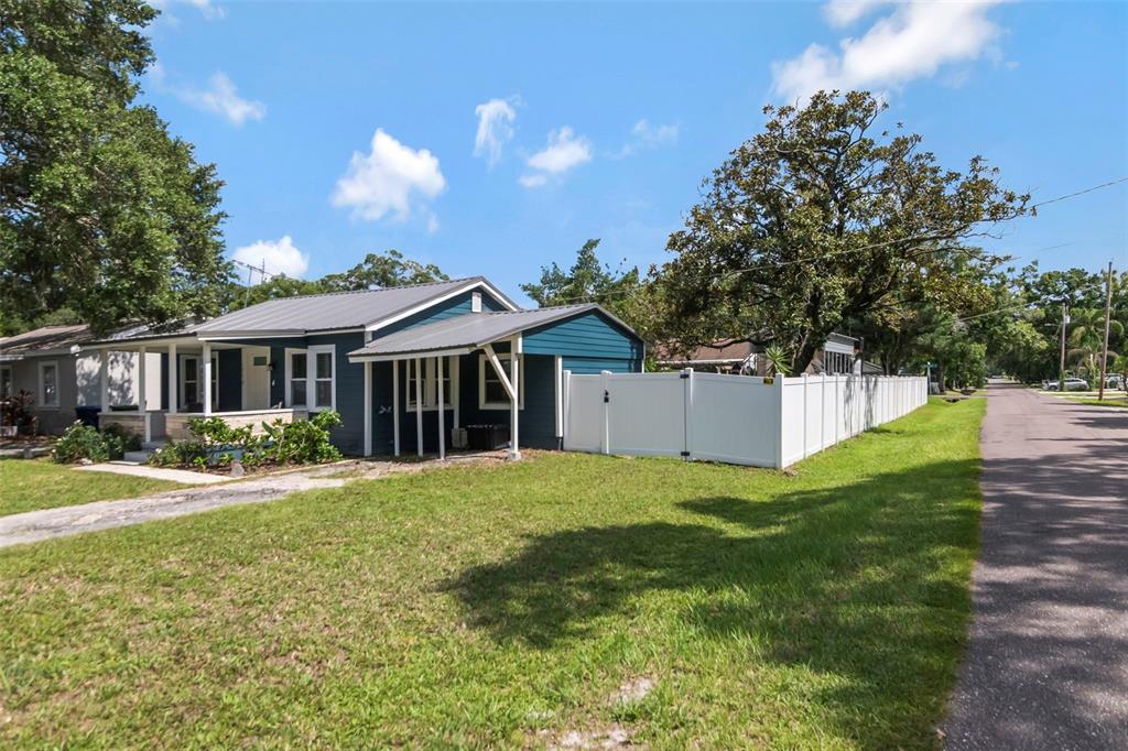 A blue house with a metal roof and a white vinyl fence sits near a road — 1716 W SITKA STREET, TAMPA, FL