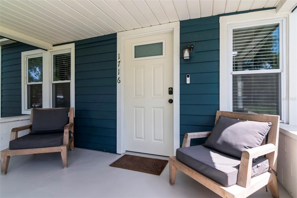 A covered front porch features blue siding, a white door, and two wooden armchairs — 1716 W SITKA STREET, TAMPA, FL