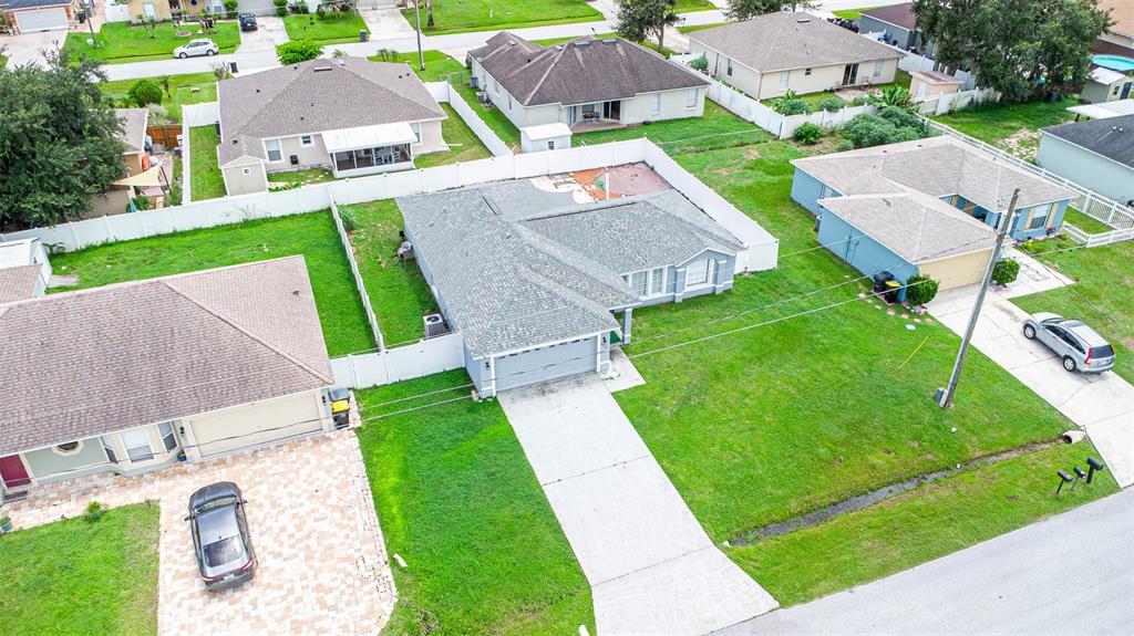 An aerial view shows a suburban neighborhood with several single-family homes and their surrounding yards — 559 HUMMINGBIRD COURT, POINCIANA, FL