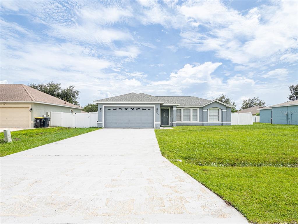 A single-story house with a gray exterior, a two-car garage, and a concrete driveway — 559 HUMMINGBIRD COURT, POINCIANA, FL