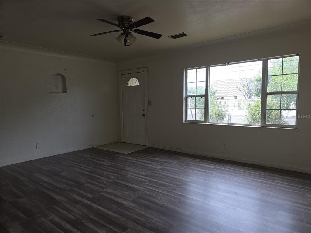 A living room features gray wood-look flooring, a ceiling fan, and a large window — 1800 22ND AVENUE S, ST PETERSBURG, FL