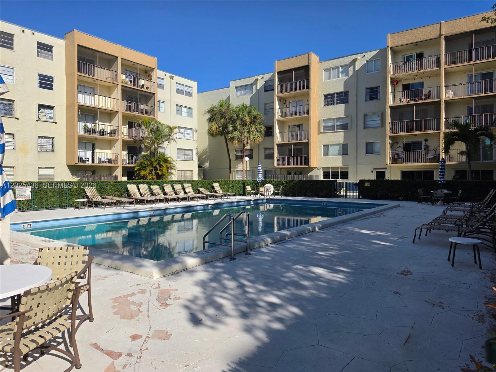 An outdoor swimming pool is surrounded by lounge chairs and multi-story apartment buildings — 14250 SW 62nd St # 409, Miami FL 33183, MIAMI, FL