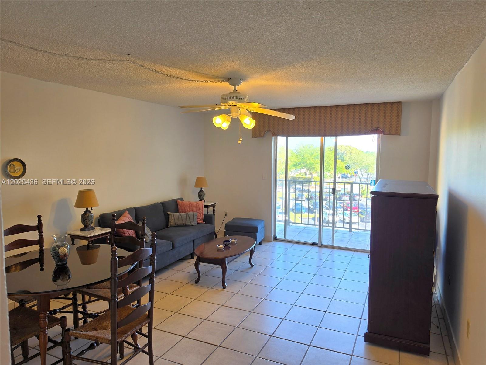 A living and dining area features tile flooring, a ceiling fan, and a sliding glass door — 14250 SW 62nd St # 409, Miami FL 33183, MIAMI, FL