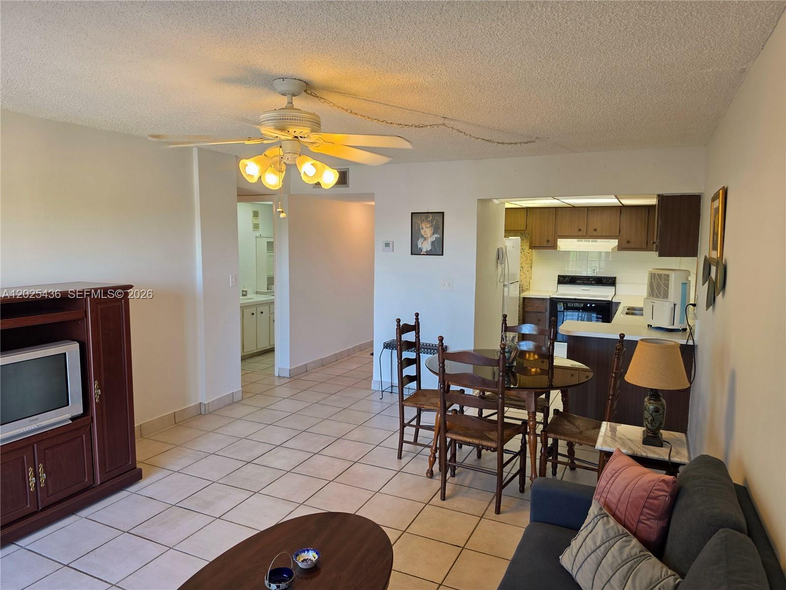 An open-concept living and dining area features tile flooring, a ceiling fan, and a kitchen — 14250 SW 62nd St # 409, Miami FL 33183, MIAMI, FL