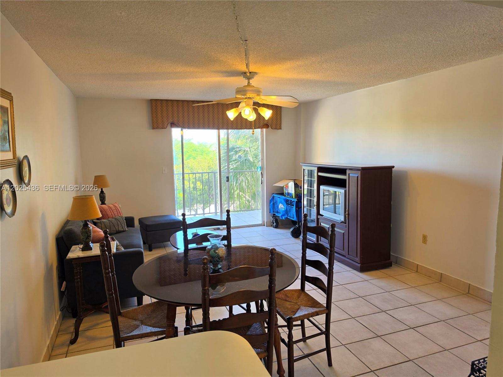 A dining and living area features tile floors, a ceiling fan, and a sliding glass door — 14250 SW 62nd St # 409, Miami FL 33183, MIAMI, FL
