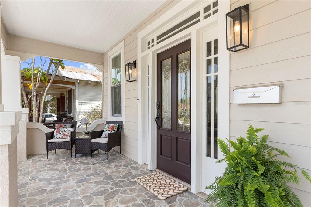 A covered front porch features stone flooring, two wicker chairs, and a dark wood door — 1917 W LEMON STREET, TAMPA, FL