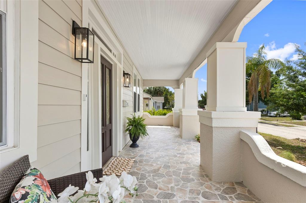 A covered front porch features stone-patterned tile flooring, white columns, and a dark wood door — 1917 W LEMON STREET, TAMPA, FL