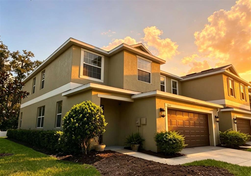 A two-story tan stucco house with a brown garage and a sunset sky background — 8505 BROKEN WILLOW COURT, TAMPA, FL