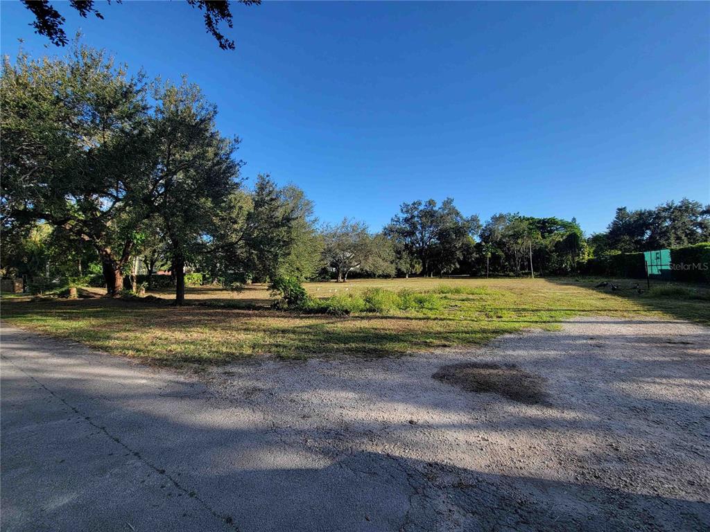 A vacant, grassy lot with mature trees is viewed from a paved road — tbd SW 93RD STREET, MIAMI, FL