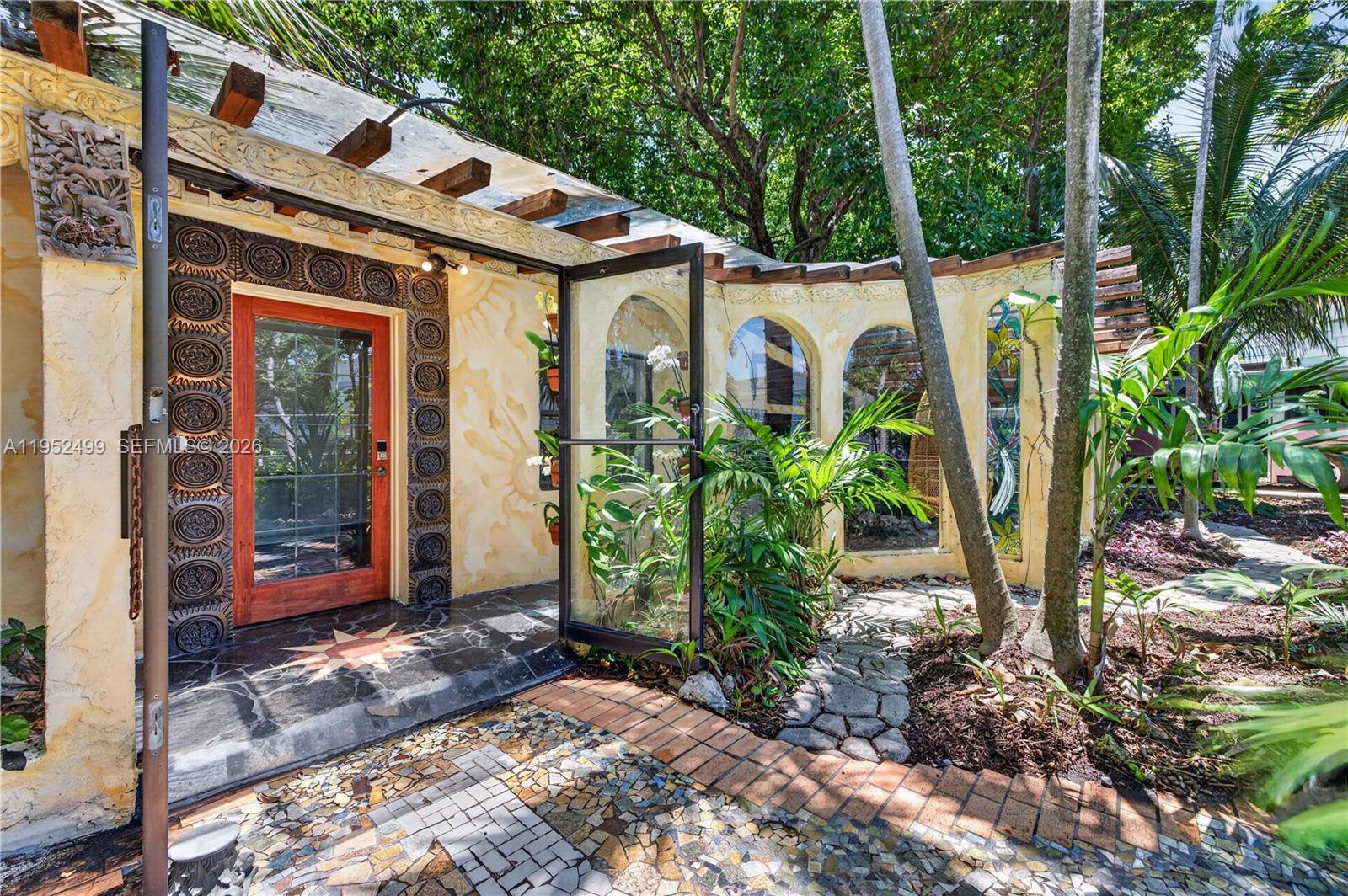 An exterior view of a house entrance with a decorative door, arched windows, and landscaping — 732 NW 43rd Ct, Oakland Park FL 33309, OAKLAND PARK, FL