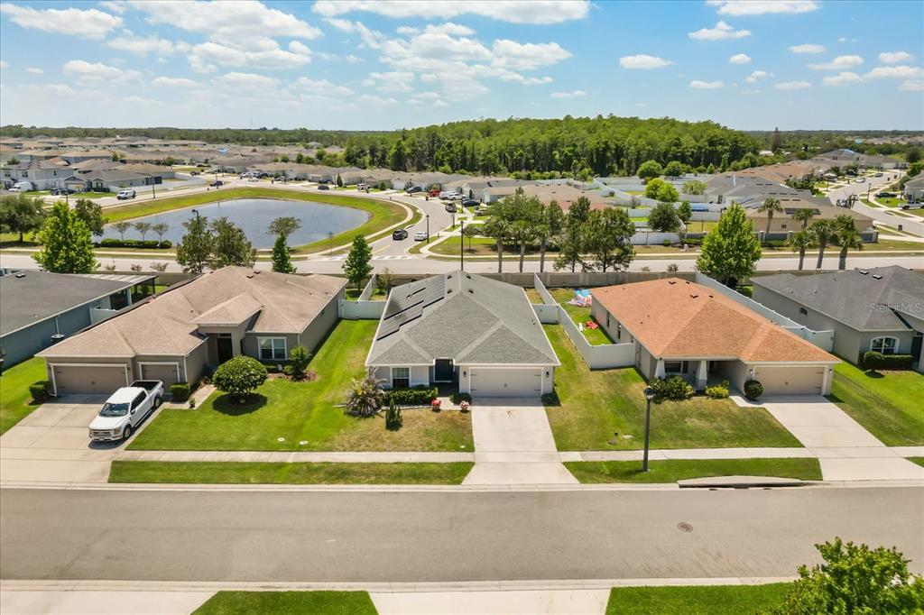 An open-concept living room and kitchen featuring wood-look flooring, a large sectional, and white cabinetry — 4531 CALUMET DRIVE, ST CLOUD, FL