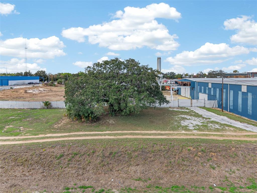 An aerial view shows a large tree on a grassy lot next to industrial buildings — HWY 17 92 N, HAINES CITY, FL