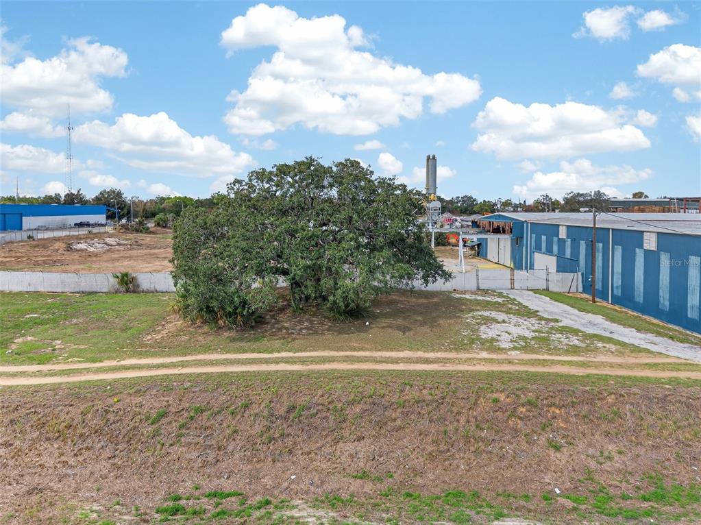 An aerial view shows a large tree on a grassy lot next to industrial buildings — HWY 17 92 N, HAINES CITY, FL