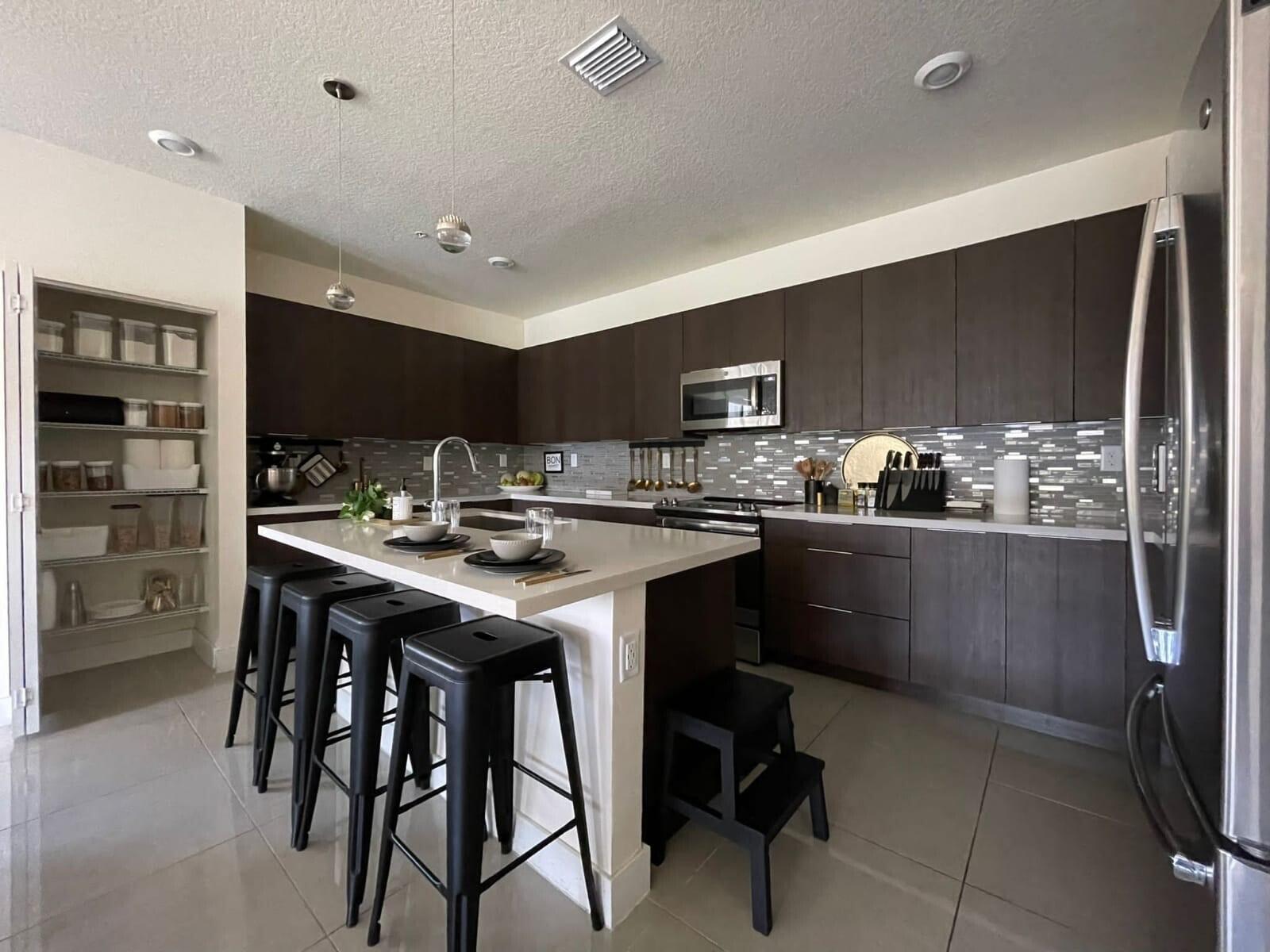 A modern kitchen features dark wood cabinets, a white quartz island, and stainless steel appliances — 4713 NW 84th Court, Doral FL 33166, DORAL, FL