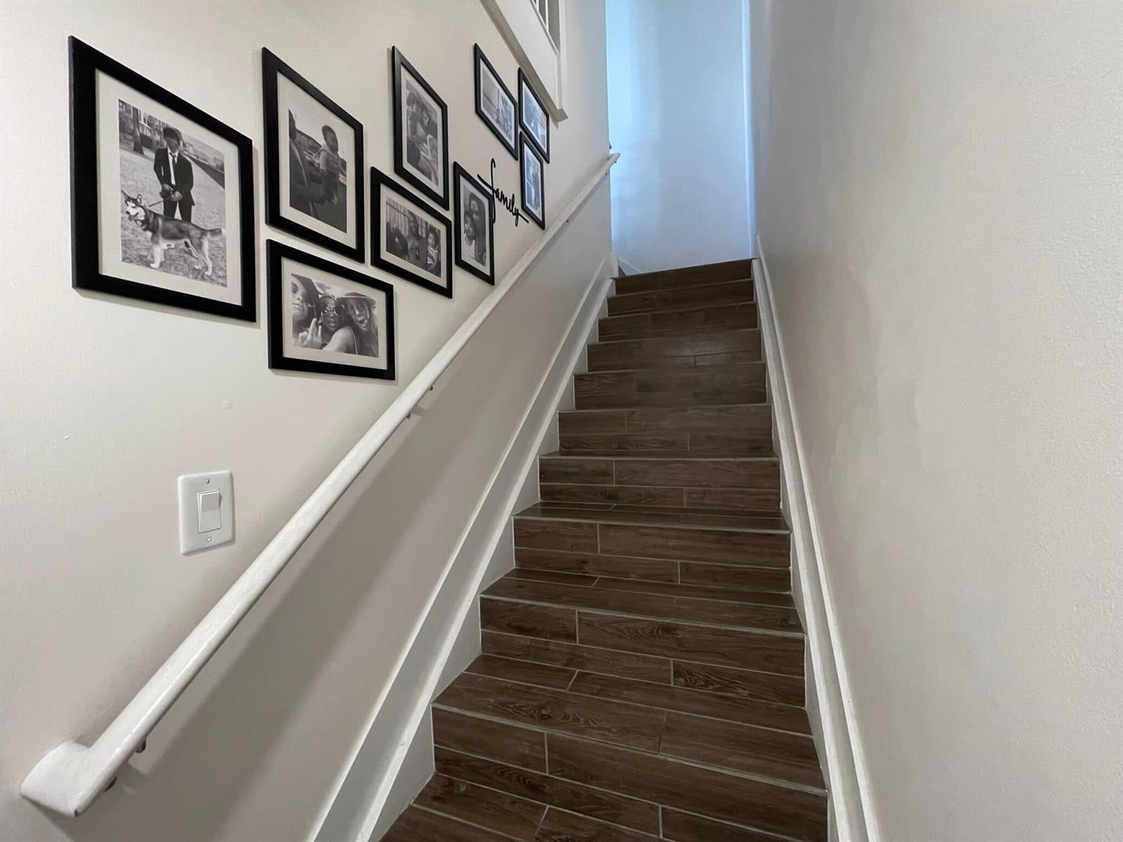 A staircase with wood-look tile steps and a white handrail features a gallery wall — 4713 NW 84th Court, Doral FL 33166, DORAL, FL