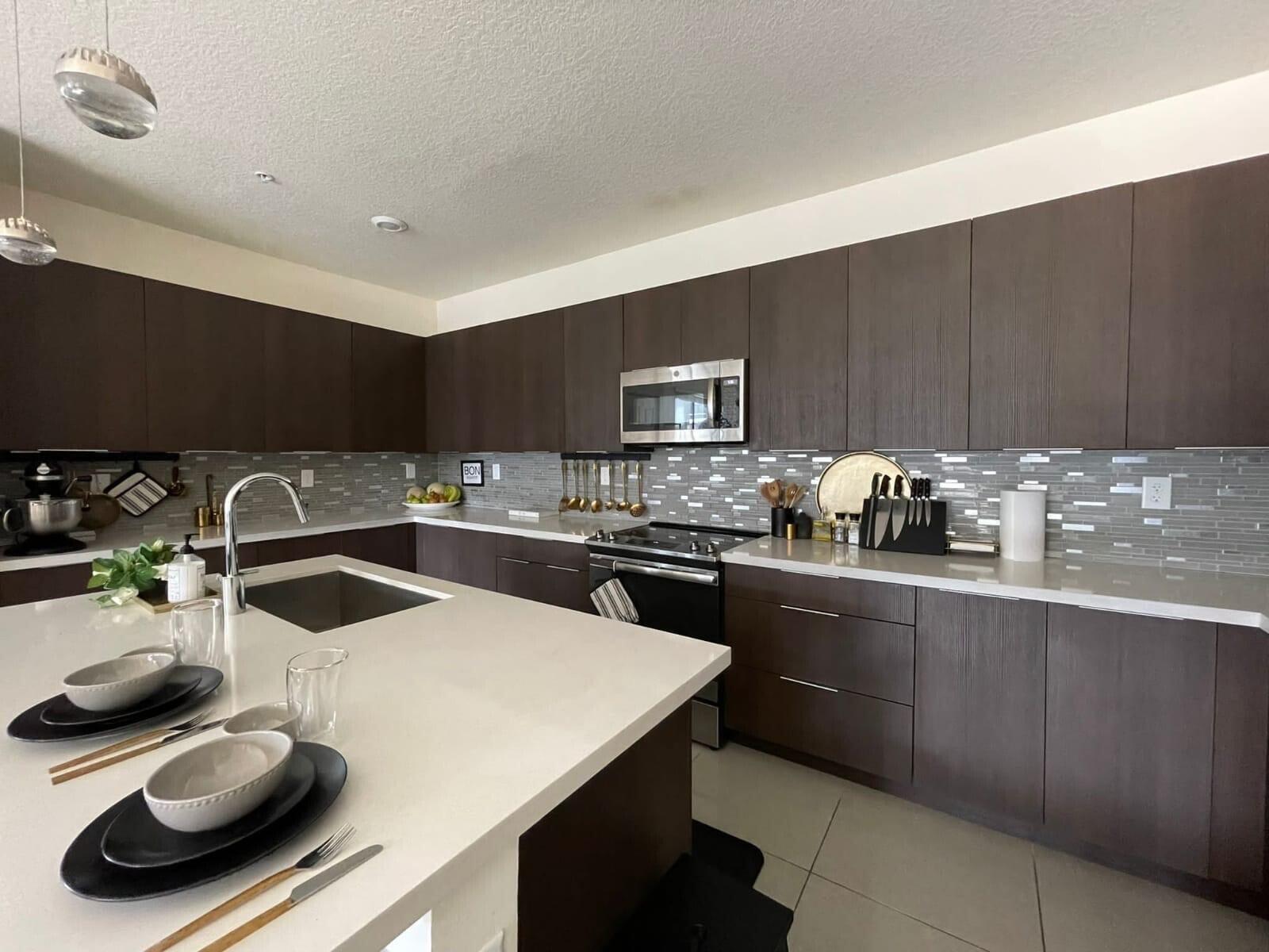 A modern kitchen features dark wood cabinets, white countertops, a center island, and tiled backsplash — 4713 NW 84th Court, Doral FL 33166, DORAL, FL
