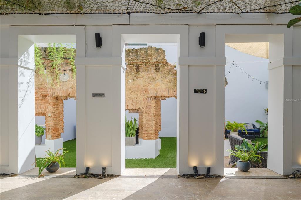 A white colonnade frames views of a courtyard with brick ruins and artificial grass — 259 & 261 CALLE DE SAN SEBASTIAN, SAN JUAN, PR