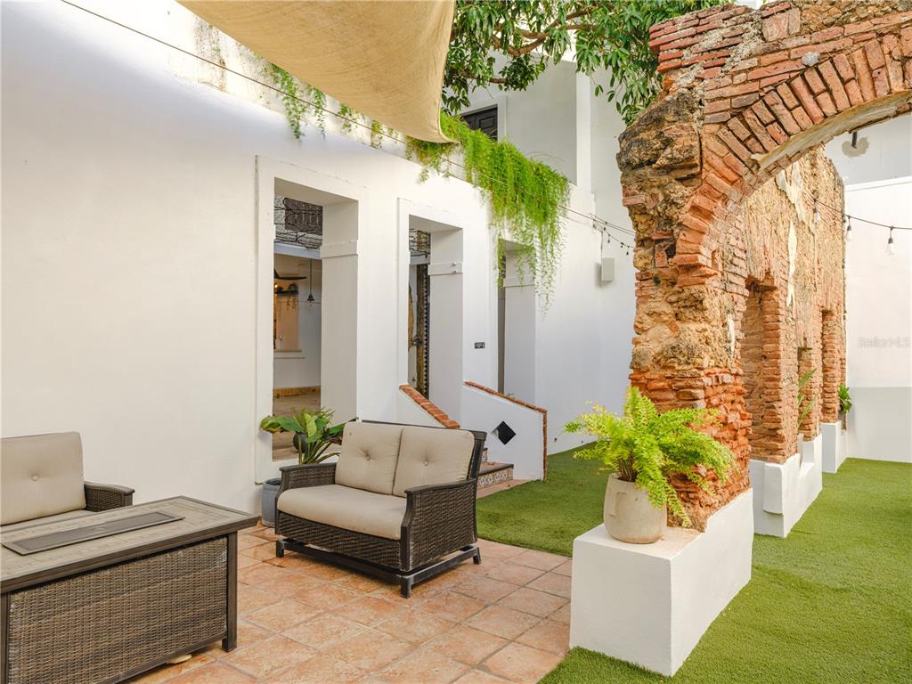 An outdoor patio features a brick archway, a wicker sofa, and artificial turf — 259 & 261 CALLE DE SAN SEBASTIAN, SAN JUAN, PR