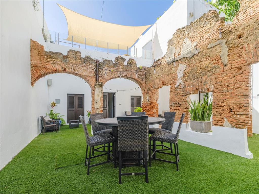 An outdoor patio features a dining set on artificial turf surrounded by historic brick ruins — 259 & 261 CALLE DE SAN SEBASTIAN, SAN JUAN, PR