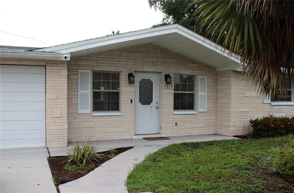 A single-story house with light-colored brick siding, a white front door, and an attached garage — 4619 IRENE LOOP, NEW PORT RICHEY, FL