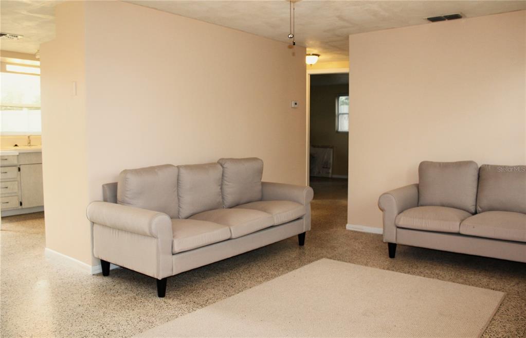 A living room features two light-colored sofas, a beige area rug, and speckled flooring — 4619 IRENE LOOP, NEW PORT RICHEY, FL