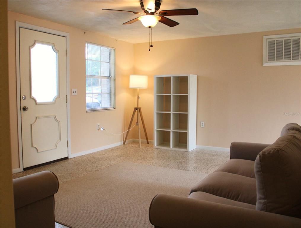 A living room features a beige sofa, a white shelving unit, a floor lamp, and a ceiling fan — 4619 IRENE LOOP, NEW PORT RICHEY, FL